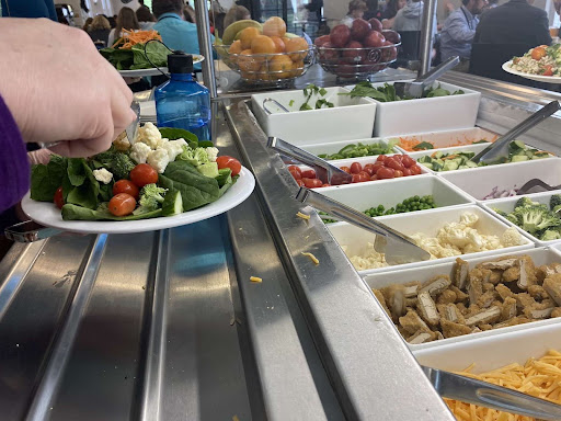 Scooping chicken onto her plate in the MICDS dining hall, a teacher takes advantage of the rotating selection of salad toppings, including two different types of greens, in-season vegetables, and a composed salad.